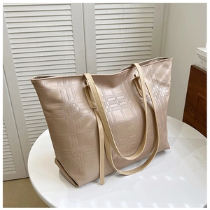 Close-up of beige tote bag featuring textured grid pattern and long handles