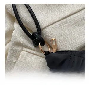 Close-up of golden metal rings and knot detail on a black quilted shoulder bag