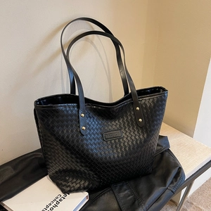 Minimalist black woven leather tote bag with gold hardware and shoulder strap