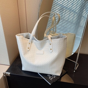 White woven tote bag with double handles and fashion logo on a stylish table display