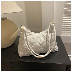 Detail of white quilted nylon shoulder bag with golden hardware and luxury texture