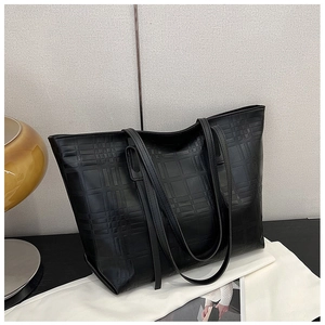 Detail of black tote bag with textured plaid embossing and minimalist matte leather finish