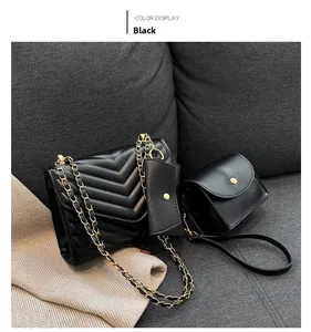 Dettaglio del set borsa trapuntata nera con catena e cuciture a V su tessuto grigio