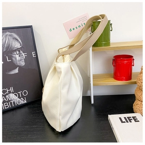 Detail view of cream canvas tote bag with khaki handles on a wooden tabletop