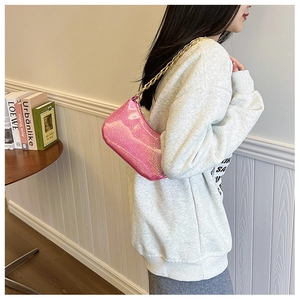 Close-up of pink glittery shoulder bag with chunky gold chain strap and zipper detail