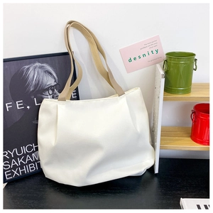 Detail of white canvas tote bag with khaki strap in a minimalist lifestyle setting