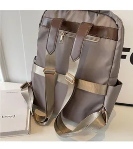 Detail of light grey commuter backpack showing back anti-theft pocket and golden metal buckles