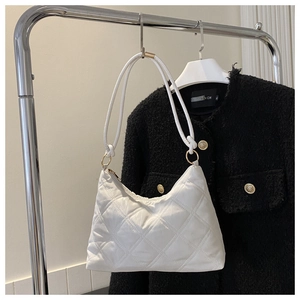 Detailed view of white quilted hobo bag with diamond stitching on black background