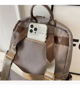 Detail of grey nylon backpack with brown leather trim showing the rear zipper pocket