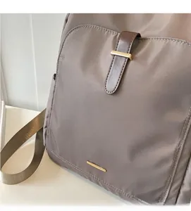 Detail of taupe commuter backpack showing soft fabric texture and golden buckle closure