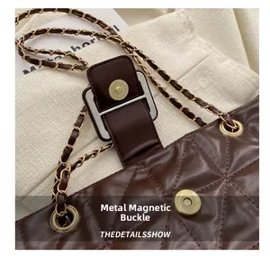 Detail of quilted brown leather tote featuring vintage gold H-shaped magnetic snap closure