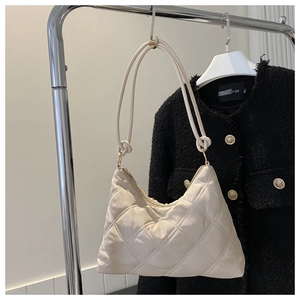 Detail of cream quilted hobo bag with diamond stitching and knotted shoulder straps