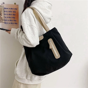Minimalist black canvas tote bag with contrast beige shoulder straps and front zipper pocket