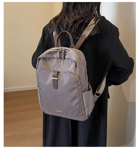 Detail view of khaki nylon laptop backpack with brown leather straps and gold zippers