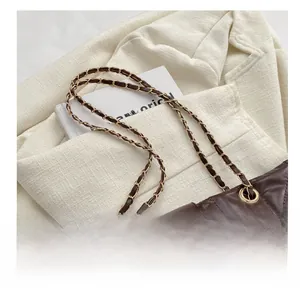 Detail of dark coffee quilted tote bag with chain strap and iconic square buckle accent