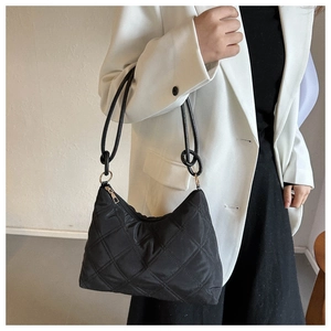 Detailed view of black quilted nylon shoulder bag with silver hardware and chic chain strap