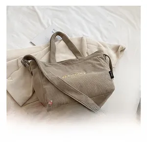 Detail of light brown corduroy tote bag showing fashion embroidery and sturdy zipper closure