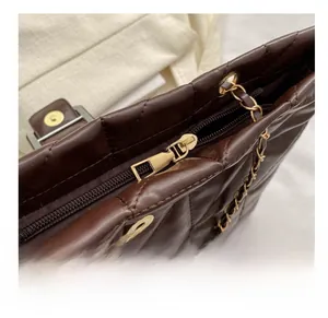 Close-up of smooth gold zipper and luxury quilted leather detail on brown tote bag