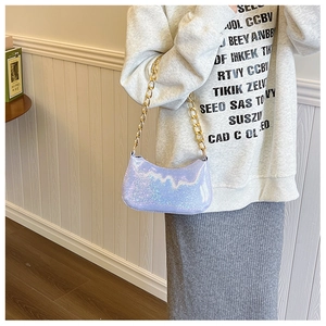 Side view of purple iridescent baguette bag with thick gold chain handle on model