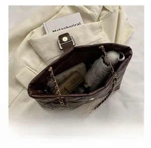 Internal view showing large storage capacity of brown quilted tote bag with chain strap