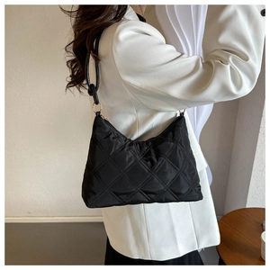 Detail of black quilted shoulder bag featuring premium nylon texture and silver buckles
