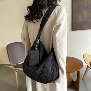 Detail of black quilted tote bag with heart stitching pattern and mini pouch on model