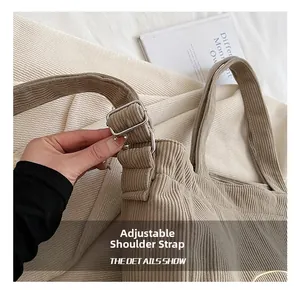 Detail of beige corduroy tote bag showing adjustable wide strap and silver metal buckle