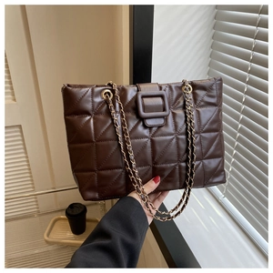 Close-up of dark brown quilted tote bag with golden chain strap and leather buckle detail
