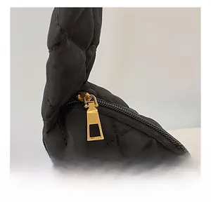 Détail de la fermeture éclair dorée et du tissu matelassé noir sur un grand sac cabas