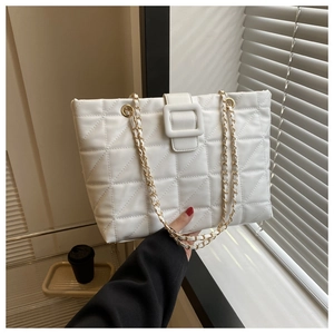 Close-up of white quilted faux leather texture with elegant gold chain woven shoulder straps