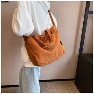 Brown corduroy tote bag detail showing ribbed texture and shoulder strap on model