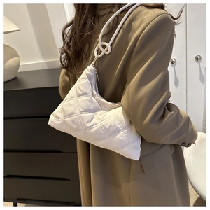 Close-up of a white quilted crossbody bag with unique triangular shape and knot detail