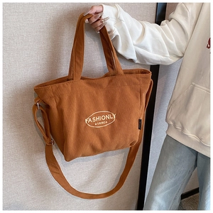 Detailed view of brown corduroy tote bag with white embroidery and dual carry straps