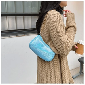 Dettaglio della borsa a tracolla azzurra glitterata con catena dorata spessa e riflessi