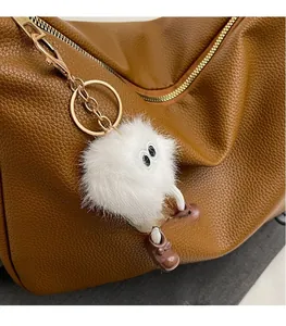 Détail macro d'un charm de monstre blanc duveteux sur un sac à main en cuir marron