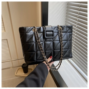 Detailed close-up of the quilted black leather tote featuring a chain strap and metal buckle