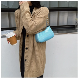Close-up of bright blue glitter shoulder bag with golden chain and knit cardigan