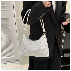 Close-up of a white quilted puffer shoulder bag with a zipper and golden rings