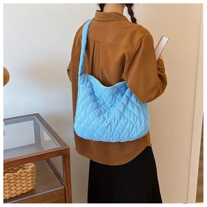 Détail d'un sac bandoulière matelassé bleu clair avec bandoulière rembourrée large