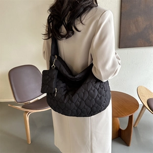 Detail of black quilted hobo bag with heart patterns and small heart charm pouch