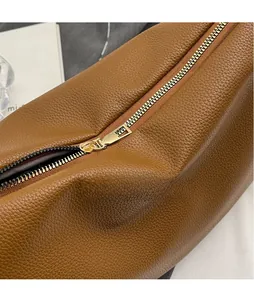 Détail de la fermeture éclair en métal doré sur le sac en cuir marron à grain fin