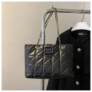 Detail of black quilted tote bag with chain strap and square buckle on hanger