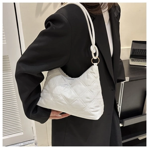 Detailed side view of white quilted shoulder bag with gold ring hardware on a model