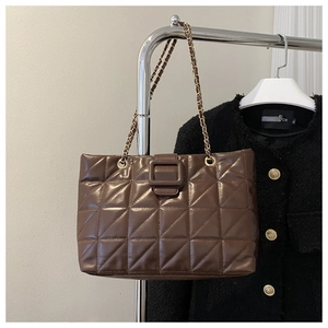 Detail of dark brown quilted tote bag with chain strap and decorative square buckle