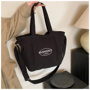 Detailed macro shot of the black corduroy tote bag showing woven strap and fashionly logo