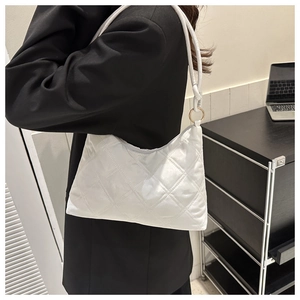 Detailed side view of white quilted shoulder bag with crescent shape and gold rings
