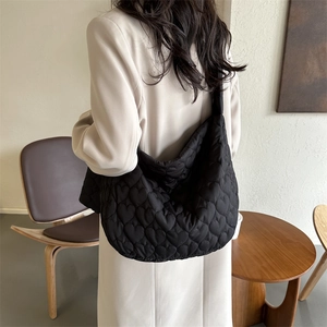 Detail view of heart quilted pattern on a black lightweight tote bag with shoulder strap