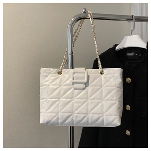 Detailed view of white quilted faux leather tote with gold metal chain strap on a hanger