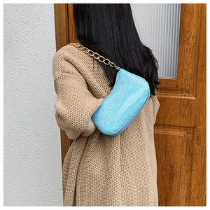 Close-up of light blue sequined shoulder bag with chunky gold chain strap and glittery texture