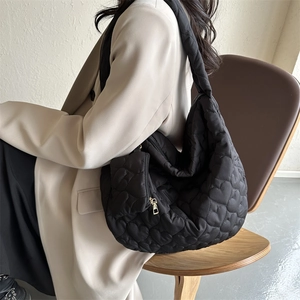 Detailed view of large black quilted tote bag with heart embroidery and mini purse charm